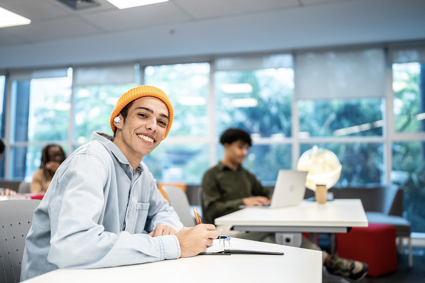 Portrait of a young university student man writing at university classroom